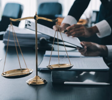 Business and lawyers discussing contract papers with brass scale on desk in office. Law, legal services, advice, justice and law concept picture with film grain effect