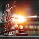 Statue of the lady of justice with scales and gavel on the desk