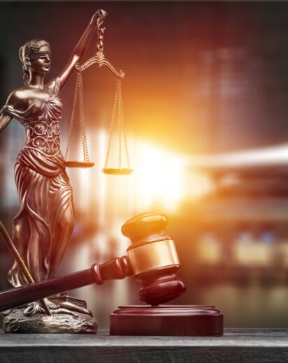 Statue of the lady of justice with scales and gavel on the desk