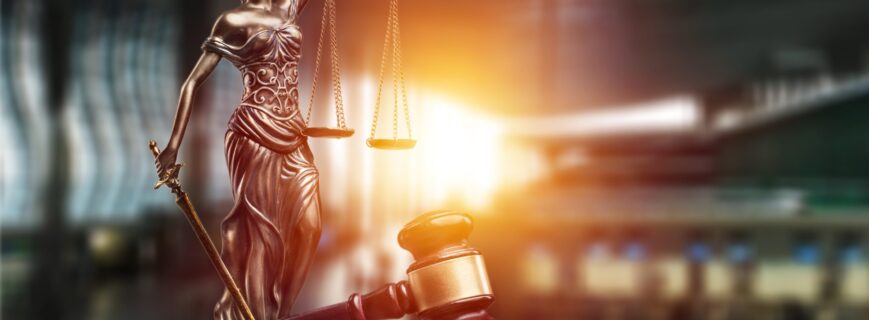 Statue of the lady of justice with scales and gavel on the desk